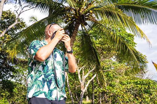 Photo with copy space of a man taking photos with a digital camera on a tropical forest
