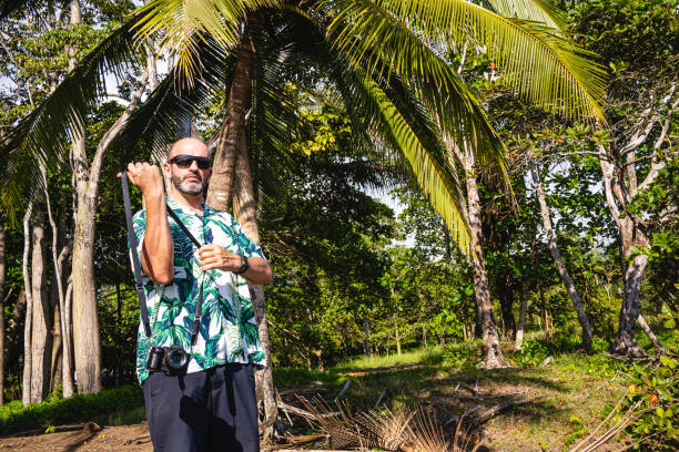 istock Man carrying a digital camera on a tropical environment 1496556026