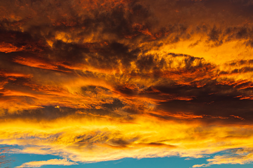 Rare dramatic storm clouds, wild looking weather system illuminated golden by sunset.