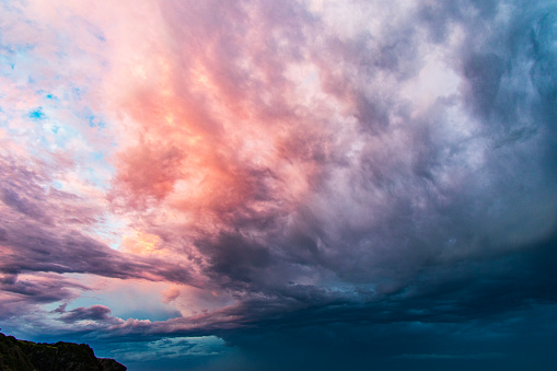 Dark moody, energetic storm cloud system illuminated by last light of day.