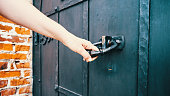 Woman's hand trying to open an old wooden door