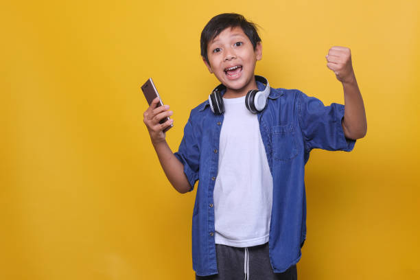 istock Happy boy gesture winning a games isolated yellow background 1496558698