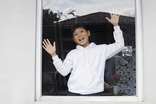 Cute brother and sister waving goodbye at camera as they leave home for school smiling