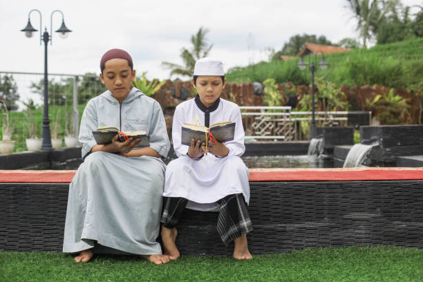 istock Siblings Learning Reading Quran Outdoors 1496559829