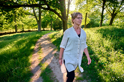Mid adult woman trekking in Danish nature. Enjoying the summer in natural parkland.