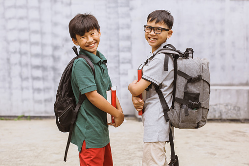 Portrait of schoolboy wearing backpack holding books outdoor