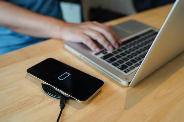 istock Charging mobile phone battery with wireless charging device in the table. Smartphone charging on a charging pad. Mobile phone near wireless charger Modern lifestyle technology concept 1496561035