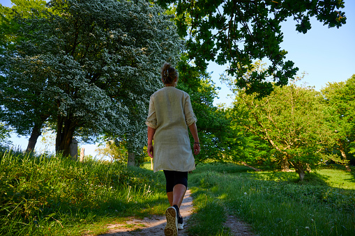 Mid adult woman trekking in Danish nature. Enjoying the summer in natural parkland.