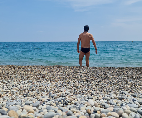 One man standing at the beach in swimsuits