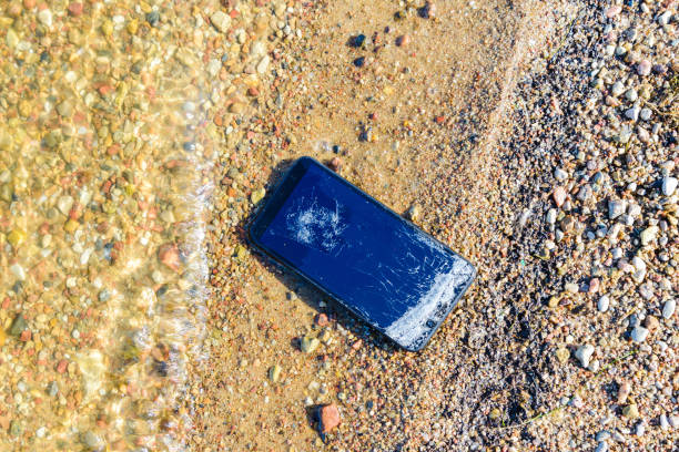 istock Vacation problems.Accident with smartphone. Smartphone falling and crashing on the beach.Cell phone damaged at sandy coast, ready to service. 1496562082