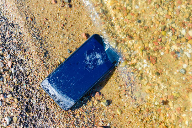 istock Vacation problems.Accident with smartphone. Smartphone falling and crashing on the beach.Cell phone damaged at sandy coast, ready to service. 1496562084