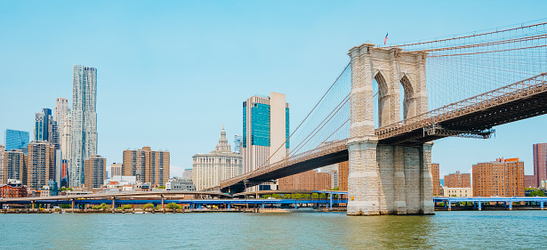 a view of the Brooklyn Bridge, above the East River, facing the Financial District and Lower Manhattan, in New York, United States, in a panoramic format to use as web banner or header
