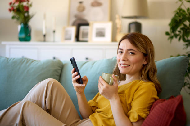 istock Woman using smartphone while drinking coffee at her home in the morning 1496567923