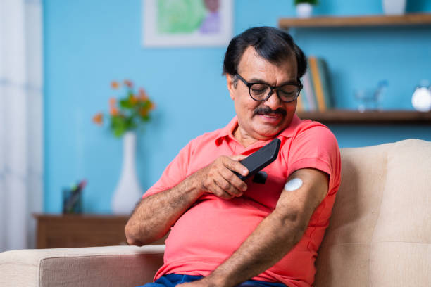 starszy mężczyzna sprawdzający poziom glukozy poprzez dotknięcie smartfonem czujnika monitorującego w domu - koncepcja opieki zdrowotnej, technologii i mdicare. - sugar level zdjęcia i obrazy z banku zdjęć