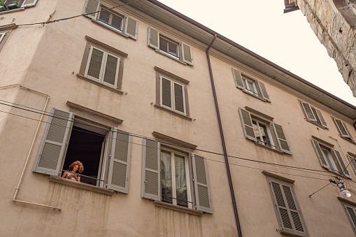 Historical center of Bergamo, upper town traditional houses Italy. Woman looking out the window