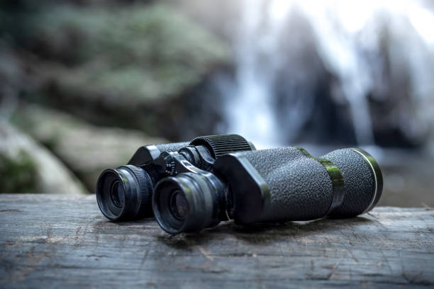 istock Close up binoculars on wood with the waterfall behind. 1496574104