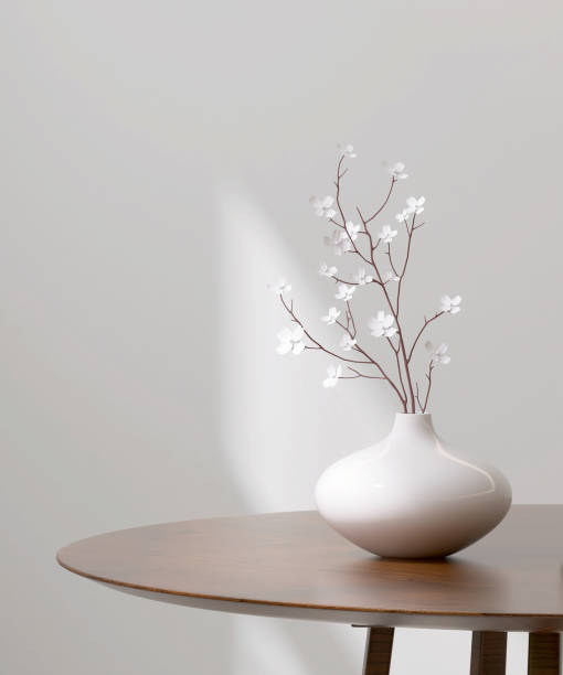 istock Empty minimal round natural wood side table podium, white flower in ceramic vase in sunlight, shadow on white wall 1496576986
