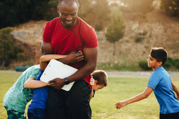 istock Kids playing with their coach during a training session in school 1496580663