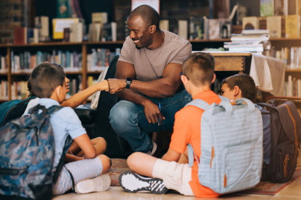 istock School teacher giving a student a fist bump in a library 1496580746