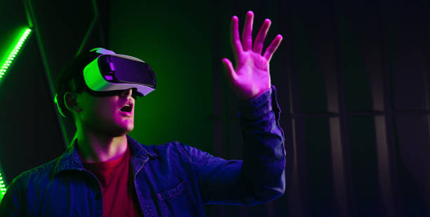 istock Young man playing an amazing game in virtual reality, wearing a VR headset and interacting with his hands 1496580818
