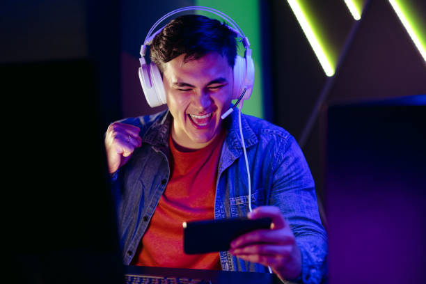 istock Young man cheering as he plays games on his mobile phone 1496580916