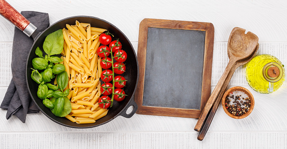 A vibrant representation of the Italian flag made with pasta, basil, and tomatoes, beautifully presented in a frying pan. Flat lay with copy space