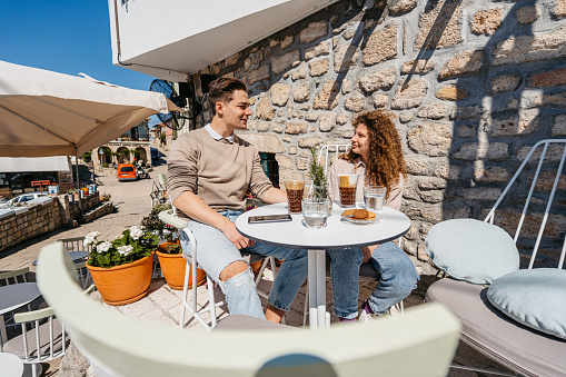 Beautiful young couple drinking coffee in a sidewalk café in Afitos, Greece.
