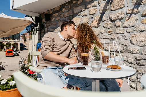 Beautiful young couple kissing in a sidewalk café in Afitos, Greece.