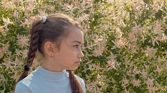 Young girl is looking away on a backgroung of flowers