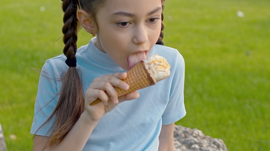A little girl eating an ice cream cone screams from an \