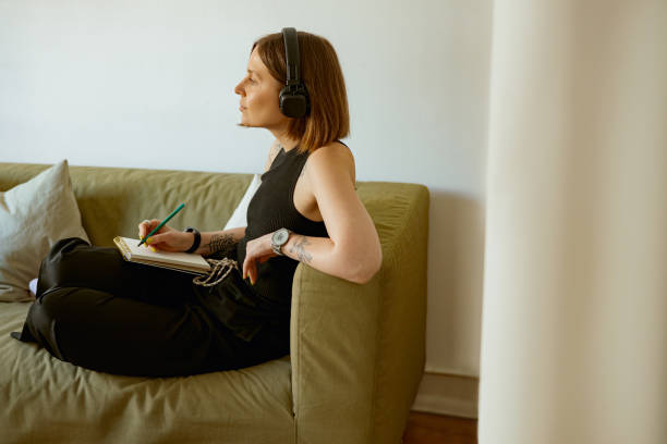 istock Female student listening webinar in headphones and making notes at home. Distance learning concept 1496587635