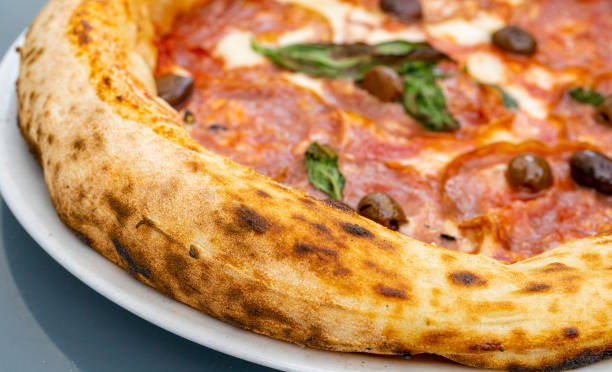 pepperoni pizza on restaurant plate, salami pizza with olives, tomatoes and mozzarella cheese - pepperoni pizza green olive italian cuisine tomato sauce imagens e fotografias de stock