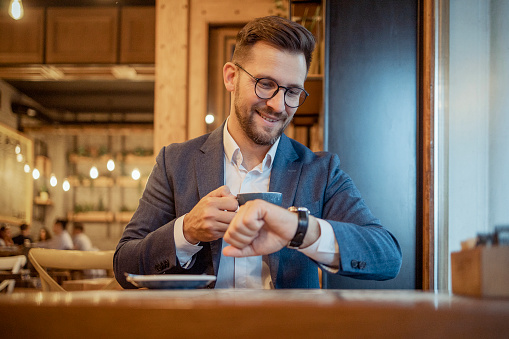 An Elegant Male Dressed in a Suit Drink Coffee in Cafe While Sitting at the Table