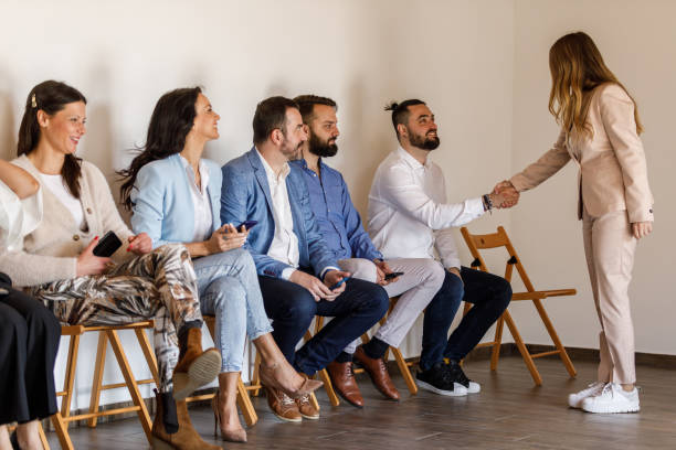 bizneswoman ściskająca dłoń kandydatom czekającym w kolejce na rozmowę kwalifikacyjną - unemployment waiting in line waiting room interview zdjęcia i obrazy z banku zdjęć