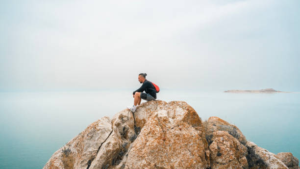istock Adventurer man on rock watching lake view 1496594430