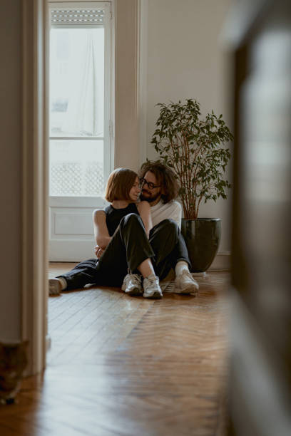 istock Smiling couple hugging and enjoying time together while sitting floor at home. Good relationship time 1496595021