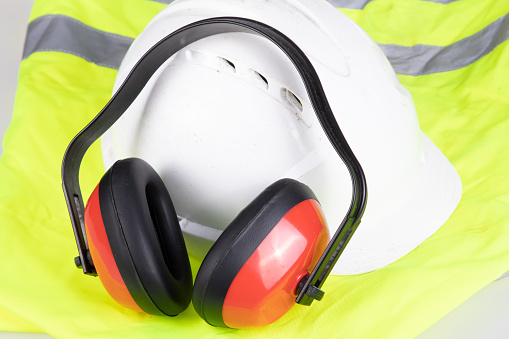 personal protective equipment for industrial security noise canceling headphones helmet and yellow reflective safety jacket on white background