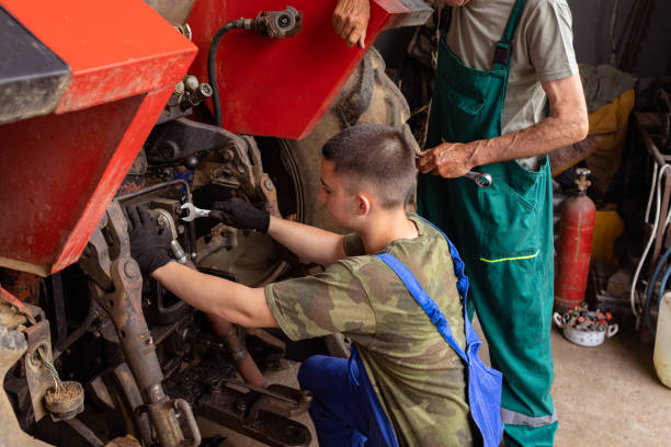 istock Man and Teenager Working on Tractor in Workshop 1496596628