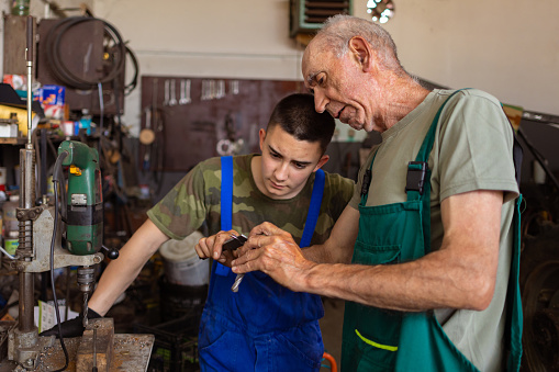 A profound connection between a mature man and his son is visible as they work in harmony in their workshop.