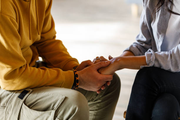 Man holding woman's hands during emotional moment at the group therapy session Close up shot of unrecognizable, compassionate man holding woman's hands during an emotional moment during a group therapy session. couples counseling stock pictures, royalty-free photos & images