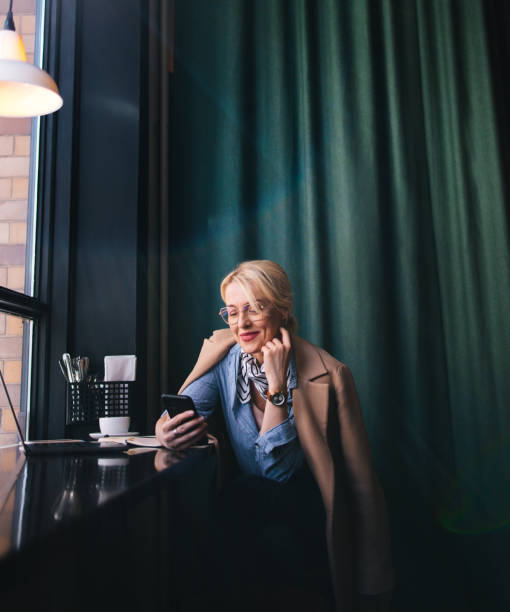 istock Smiling Business Woman Using A Mobile Phone In The Cafe 1496604475