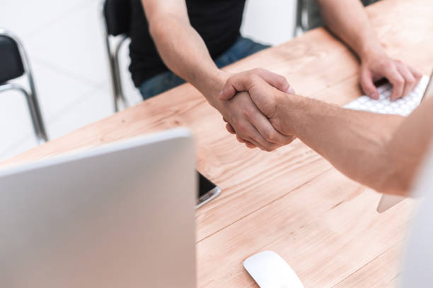 istock close up. employees shaking hands in the workplace 1496609675