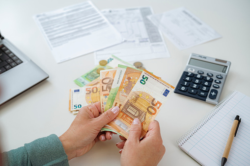 Close-up of woman's hands counting Euro banknotes planning home finances.