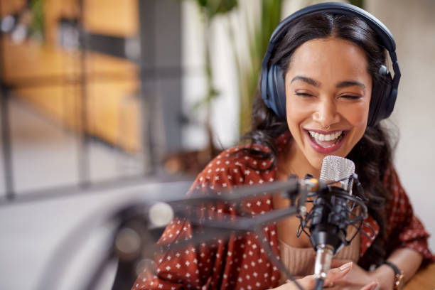 Joyful multiethnic woman recording live podcast stock photo