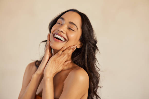 Beautiful laughing woman touching her skin with joy stock photo
