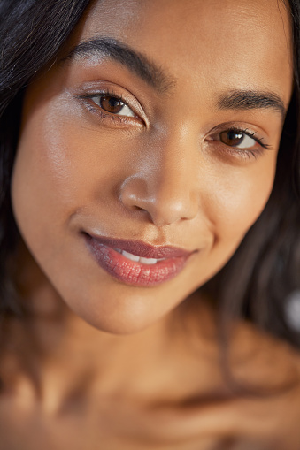 Detail of beautiful young mexican woman with healthy skin looking at camera. Latin hispanic woman with flawless skin smiling. Closeup of mexican girl following skincare routine for a healthy and smooth skin.