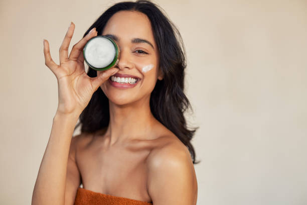 Hispanic woman holding beauty cream jar while smiling stock photo