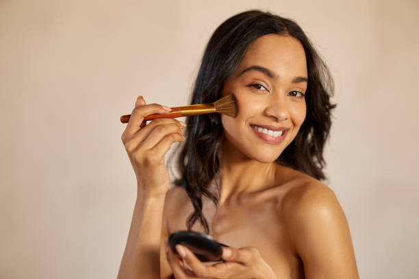 Happy latin beauty woman applying makeup powder stock photo