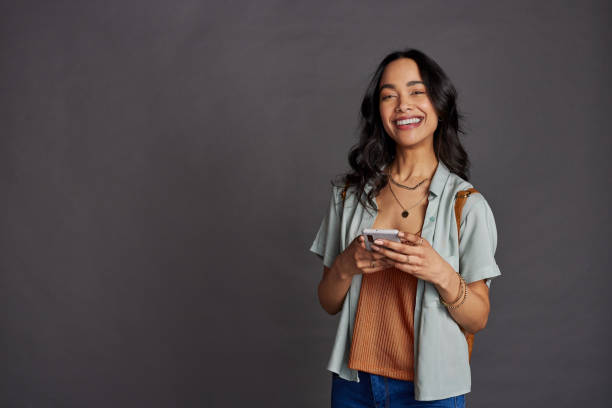 joven multiétnica usando teléfono inteligente en pared gris - latinos celular fotografías e imágenes de stock