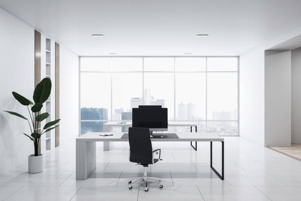 istock Front view of modern empty office interior with concrete floor, white walls and desks with computers, window with city view and furniture. Business background and workspace concept, 3D Rendering 1496626484